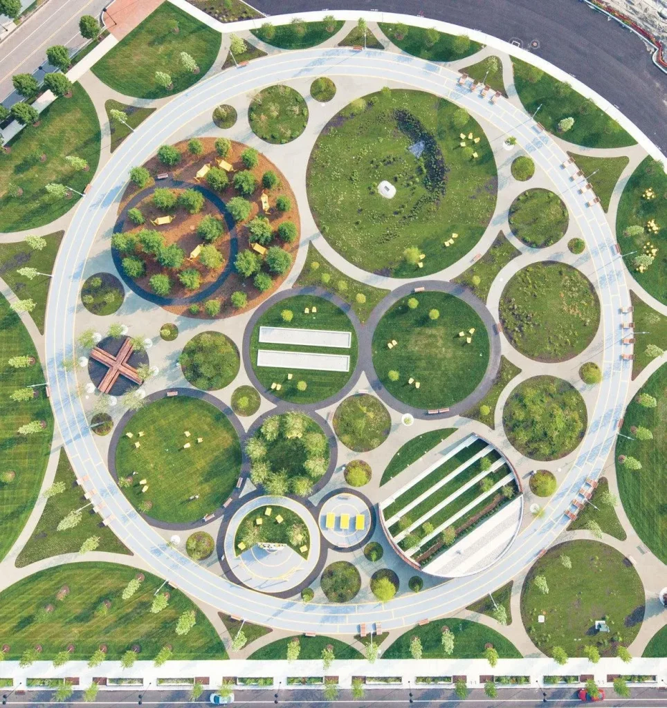 11 نکته کلیدی برای طراحی فضاهای عمومی موفق 2 نمای هوایی از یک پارک مدرن با طراحی هندسی دایرهای، شامل فضاهای سبز متعدد و مسیرهای پیادهروی منحنی.