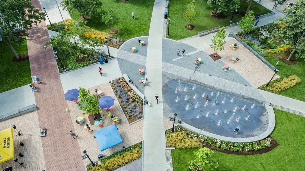 11 نکته کلیدی برای طراحی فضاهای عمومی موفق 9 نمای هوایی از پارک و پلازای شهری مدرن با فواره، مسیرهای پیادهروی و فضای سبز.