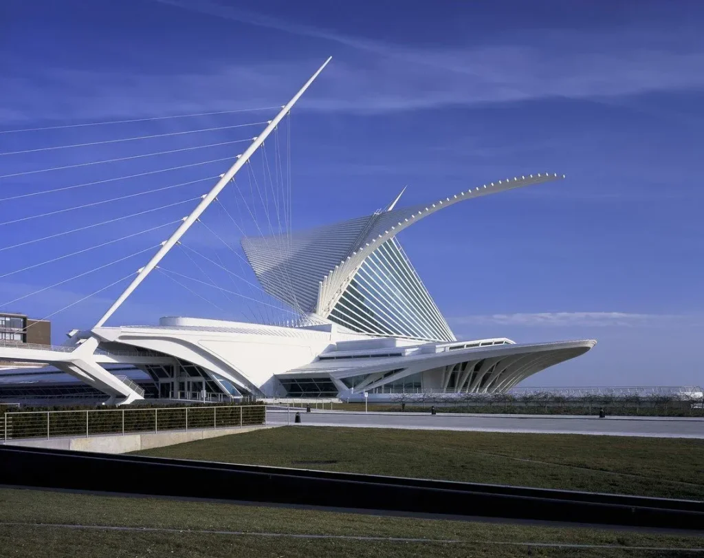 10 نمونه برجسته از معماری بیومیمتیک: الهام از طبیعت برای آیندهای پایدار 6 موزه هنر میلواکی، ساختمانی مدرن و سفید با بالهای متحرک و دکل بلند، در پسزمینه آسمان آبی.