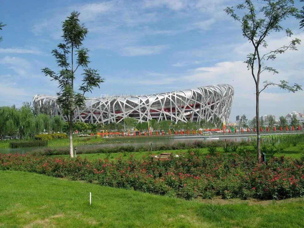 10 نمونه برجسته از معماری بیومیمتیک: الهام از طبیعت برای آیندهای پایدار 9 استادیوم آشیانه پرنده پکن در محیطی سرسبز.