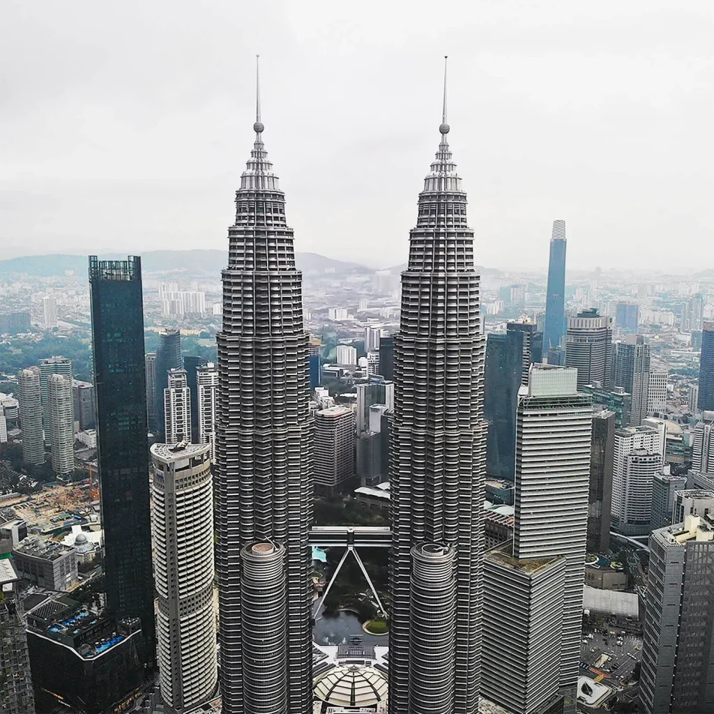 برج&zwnj;های دوقلوی آیکونیک پتروناس در کوالالامپور، مالزی، از نمای هوایی بر فراز چشم&zwnj;انداز شهری.